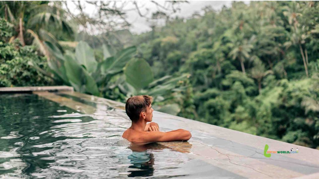 A tourist swimming in a luxurious infinity pool overlooking lush greenery in Ubud, Bali.
